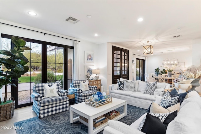 living room with a chandelier, french doors, and wood-type flooring