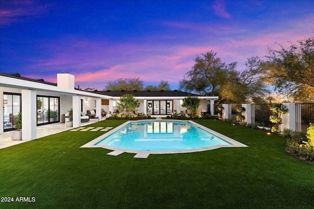 pool at dusk featuring a patio area, an outdoor hangout area, and a yard