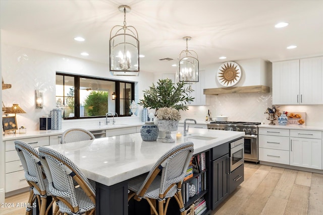 kitchen with white cabinetry, sink, pendant lighting, and a center island with sink