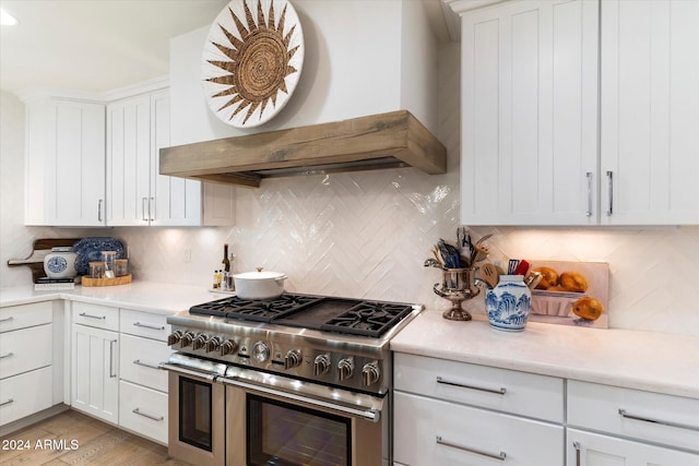 kitchen featuring premium range hood, range with two ovens, and white cabinetry