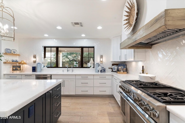 kitchen with white cabinetry, sink, hanging light fixtures, stainless steel appliances, and custom range hood