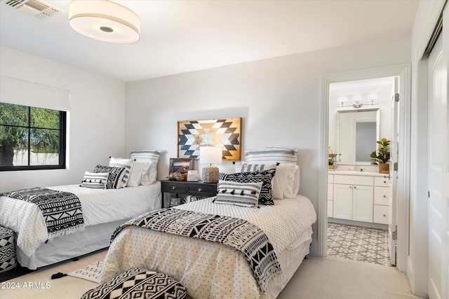 carpeted bedroom featuring ensuite bathroom and sink