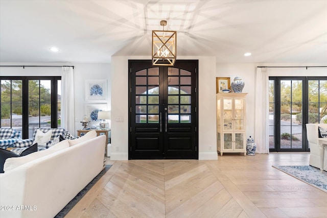 foyer with a chandelier, french doors, and light wood-type flooring