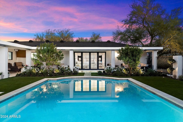 pool at dusk featuring a yard