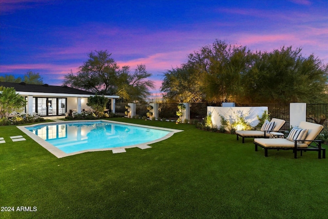 pool at dusk featuring a yard and french doors