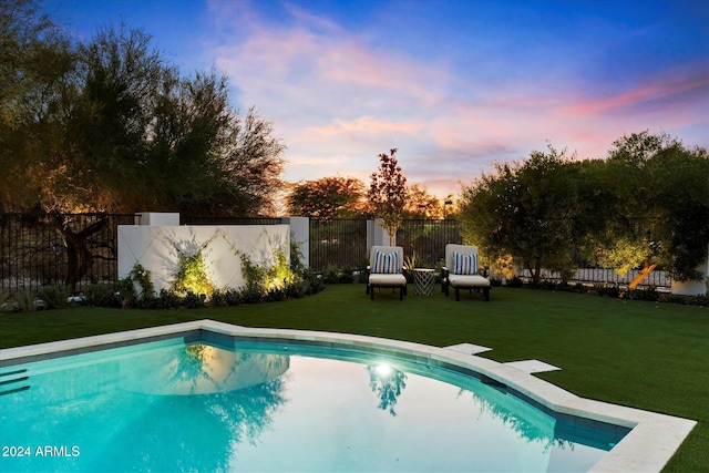 pool at dusk featuring a yard