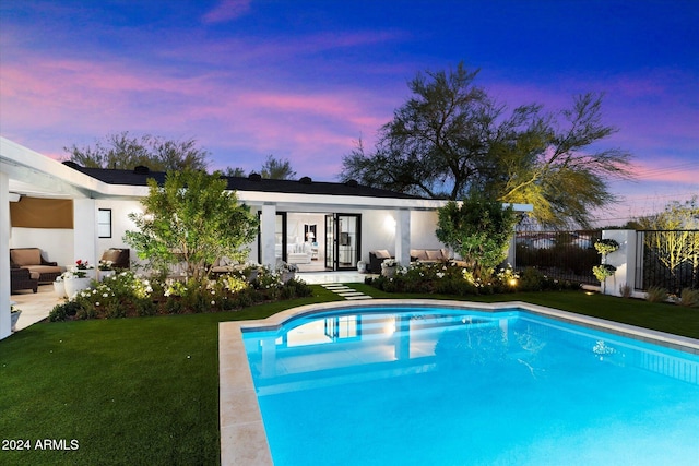 pool at dusk featuring a yard