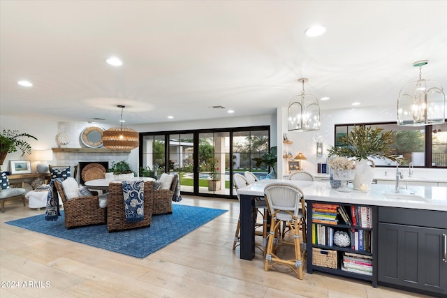 dining area with a fireplace, sink, french doors, and light hardwood / wood-style flooring