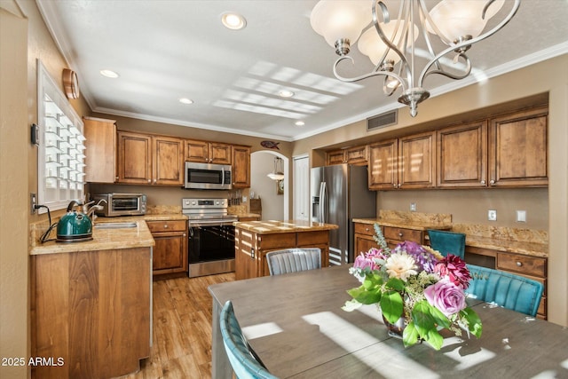 kitchen featuring ornamental molding, stainless steel appliances, a center island, and light stone counters