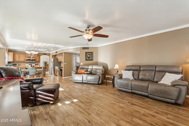 living room featuring ceiling fan with notable chandelier, light hardwood / wood-style flooring, and ornamental molding