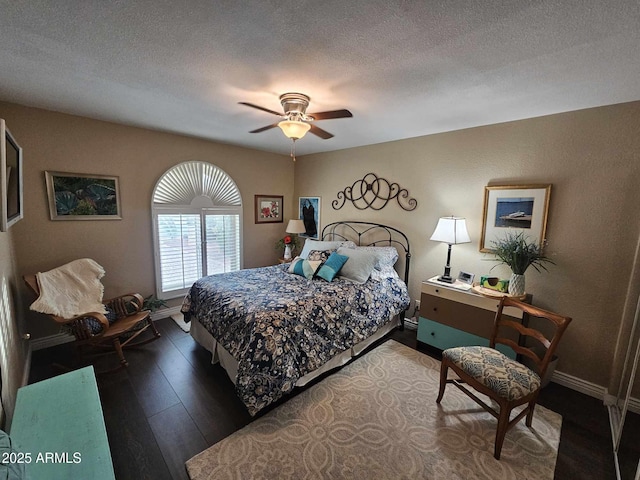 bedroom with ceiling fan, a textured ceiling, and dark wood-type flooring