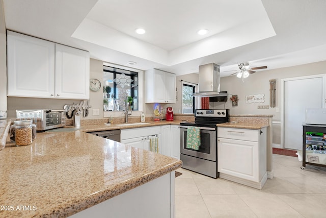 kitchen featuring light stone counters, stainless steel appliances, a raised ceiling, island range hood, and white cabinetry