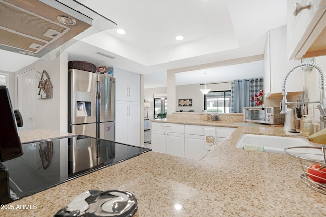 kitchen featuring sink, a raised ceiling, stainless steel refrigerator with ice dispenser, decorative light fixtures, and white cabinets