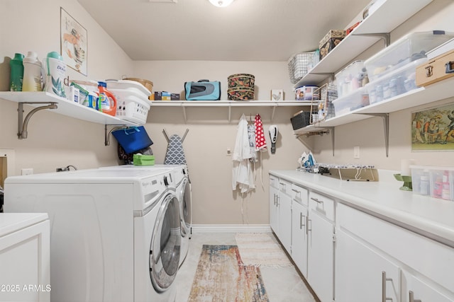 washroom featuring washing machine and clothes dryer and cabinets