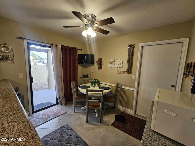 tiled dining area with ceiling fan and a textured ceiling