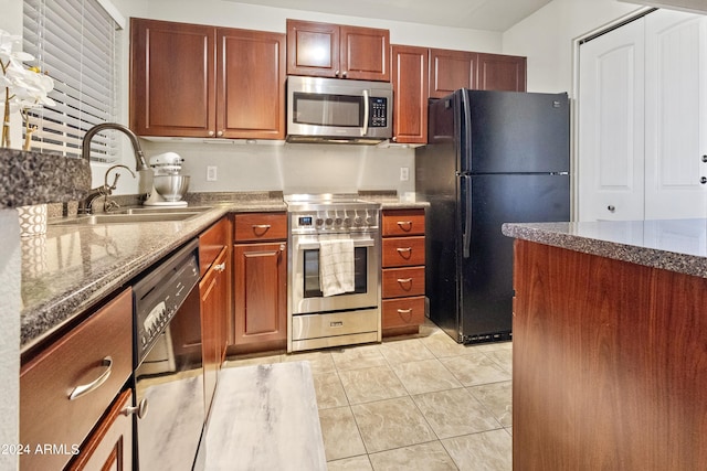 kitchen featuring stone counters, light tile patterned floors, sink, and black appliances