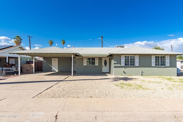 ranch-style home featuring driveway, a carport, and fence