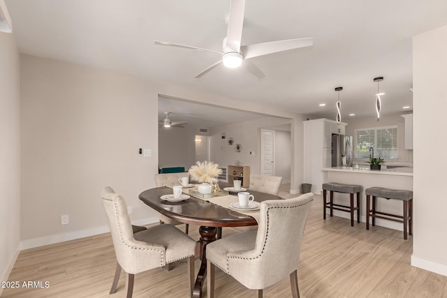 dining area with baseboards, light wood-type flooring, and a ceiling fan