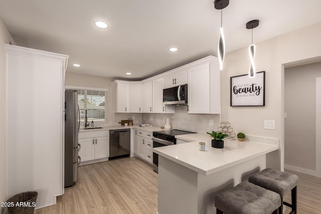 kitchen featuring white cabinets, a peninsula, stainless steel appliances, and a breakfast bar