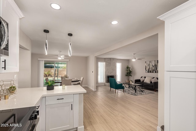 kitchen with open floor plan, light wood-style floors, ceiling fan, and white cabinetry