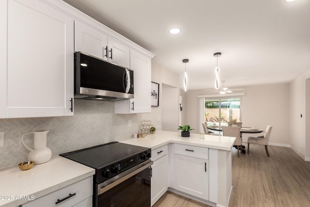 kitchen featuring backsplash, a peninsula, stainless steel microwave, white cabinets, and black / electric stove
