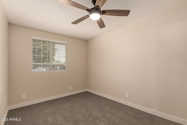 spare room with baseboards, dark carpet, and ceiling fan