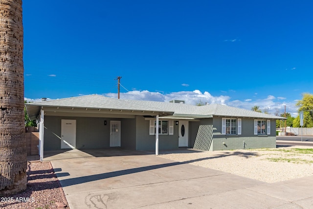 ranch-style house featuring an attached carport, driveway, and roof with shingles