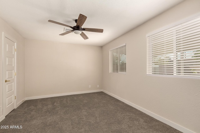 unfurnished room featuring baseboards, visible vents, dark colored carpet, and a ceiling fan
