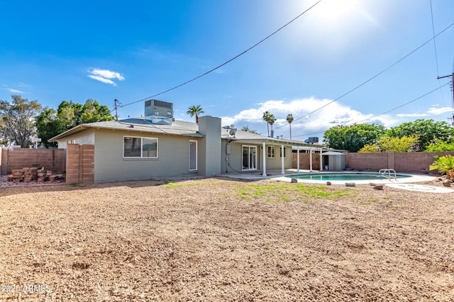 rear view of house with a fenced backyard, a patio, central AC, and a fenced in pool
