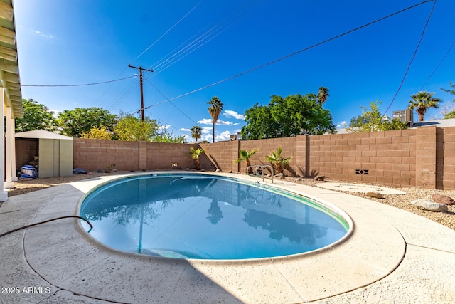 view of swimming pool featuring an outdoor structure, a fenced backyard, a fenced in pool, and a shed