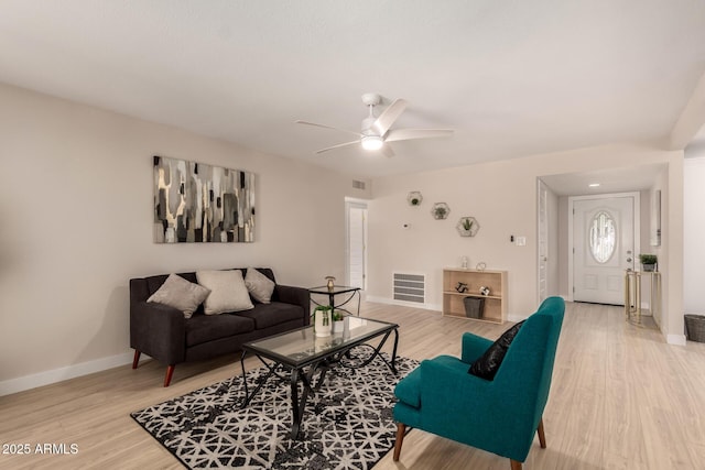 living area featuring light wood finished floors, baseboards, visible vents, and a ceiling fan