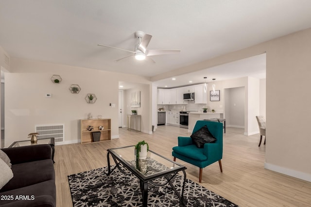 living area with light wood finished floors, baseboards, visible vents, and a ceiling fan