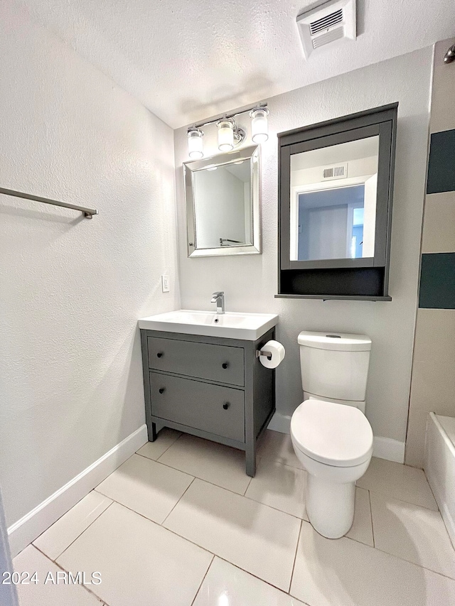 bathroom with toilet, tile patterned floors, vanity, a textured ceiling, and a bathtub