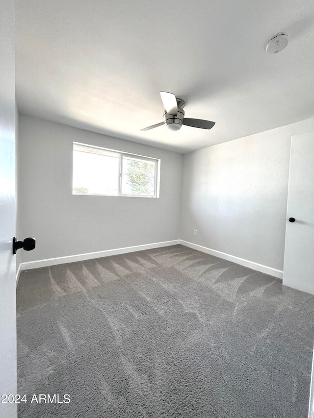 carpeted spare room featuring ceiling fan