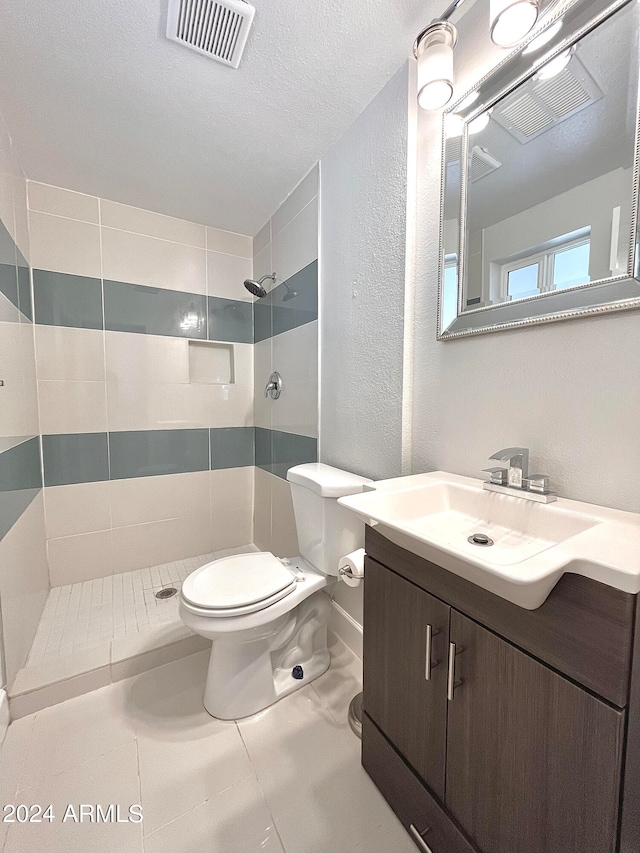 bathroom featuring tiled shower, tile patterned flooring, toilet, and vanity