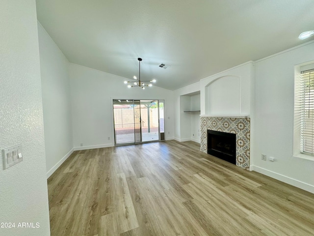 unfurnished living room with visible vents, lofted ceiling, light wood-style floors, a fireplace, and a chandelier