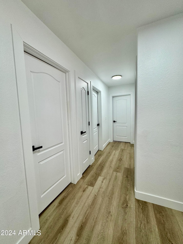 hallway featuring light wood finished floors and baseboards