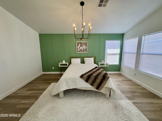 5984 W Geronimo Ct, Chandler, AZ 85226 - bedroom featuring baseboards, visible vents, wood finished floors, and an inviting chandelier