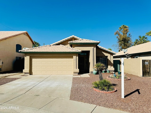 view of front of property featuring stucco siding, fence, a garage, driveway, and a tiled roof