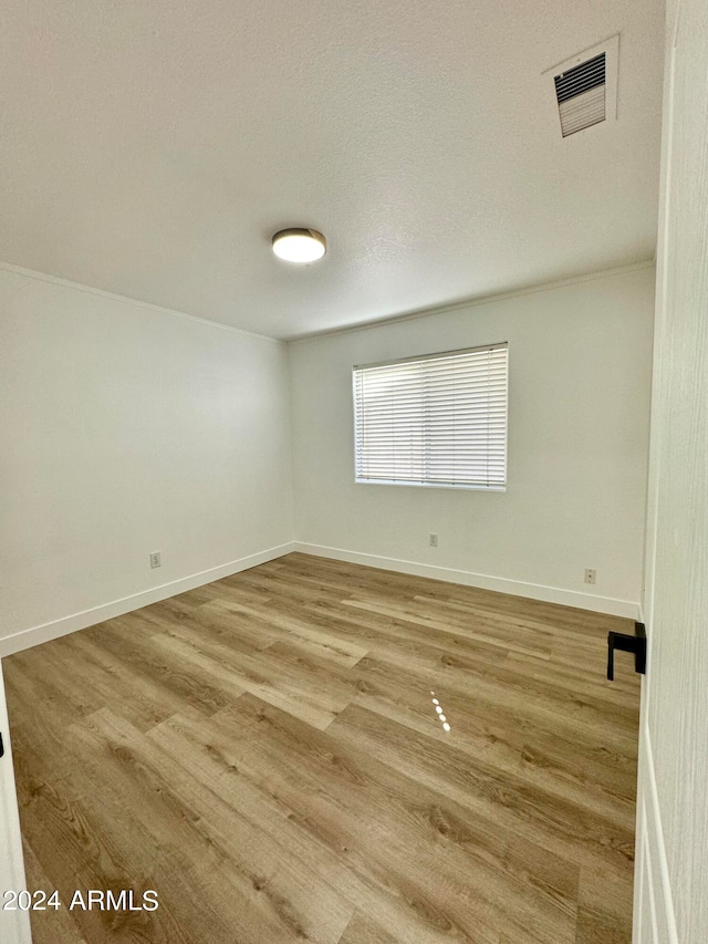 spare room featuring baseboards, visible vents, and wood finished floors