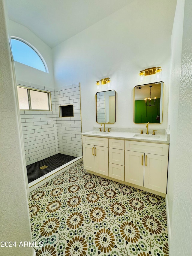 full bathroom with tiled shower, a sink, and double vanity