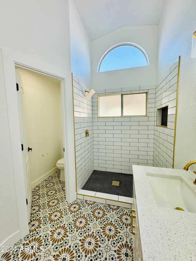 bathroom with a stall shower, toilet, lofted ceiling, tile patterned floors, and a sink