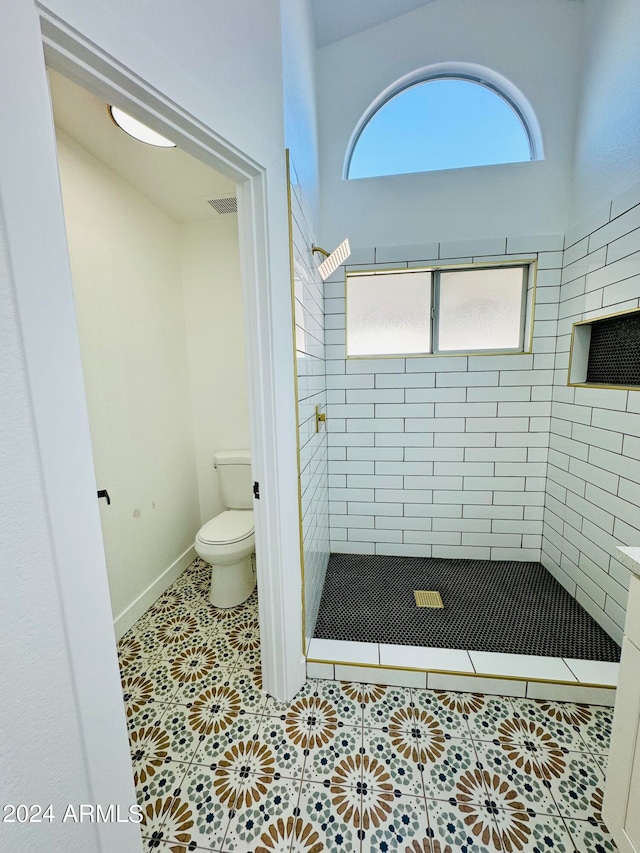 bathroom featuring visible vents, toilet, a tile shower, baseboards, and tile patterned floors