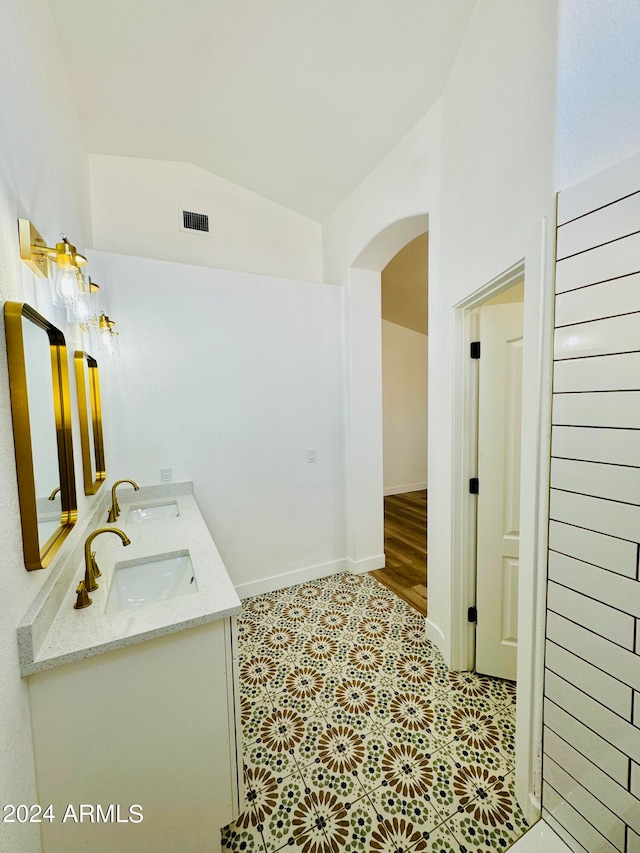 full bathroom featuring lofted ceiling, visible vents, a sink, and double vanity