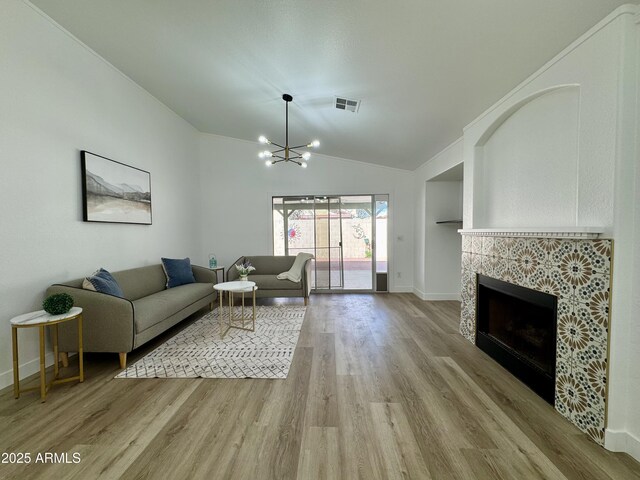 5984 W Geronimo Ct, Chandler, AZ 85226 - living area with visible vents, a tiled fireplace, wood finished floors, and an inviting chandelier