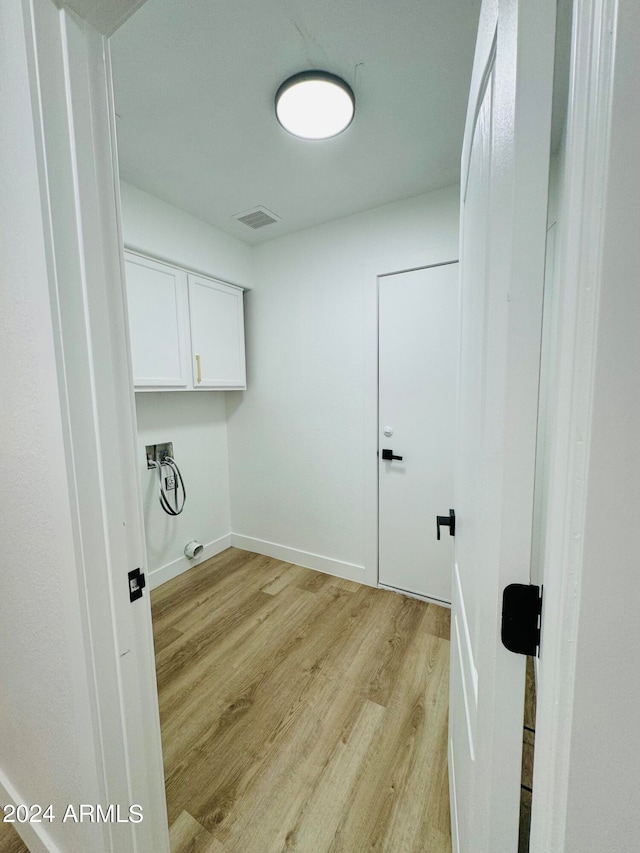 washroom featuring washer hookup, light wood finished floors, cabinet space, visible vents, and baseboards