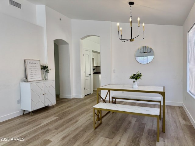 5984 W Geronimo Ct, Chandler, AZ 85226 - dining area with an inviting chandelier, light wood-style flooring, arched walkways, and visible vents