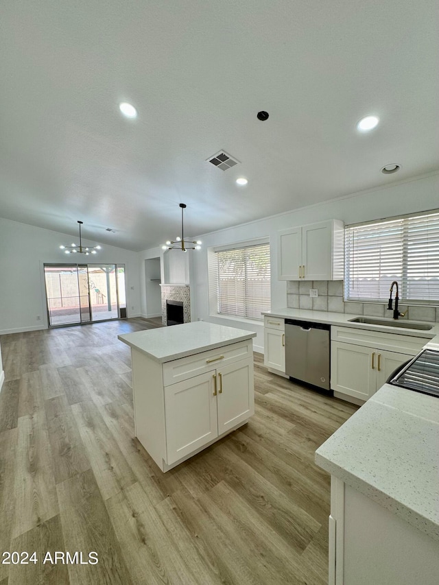 kitchen featuring visible vents, dishwasher, a fireplace, white cabinetry, and a sink