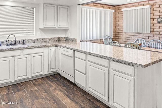 2452 Daisy Trl, Forest Lakes, AZ 85931 - kitchen with dishwasher, a sink, a peninsula, white cabinetry, and brick wall
