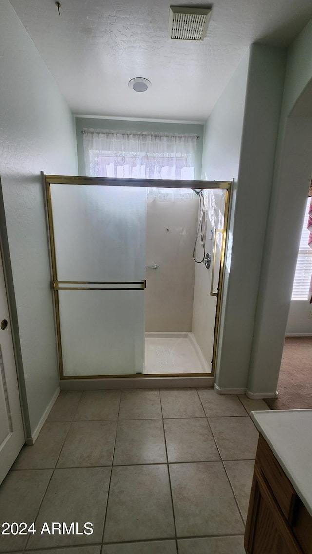 bathroom featuring tile patterned flooring, a shower with shower door, and a textured ceiling